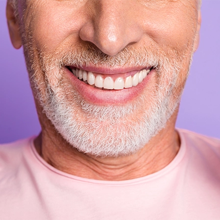 Senior man with white teeth smiling in front of purple background
