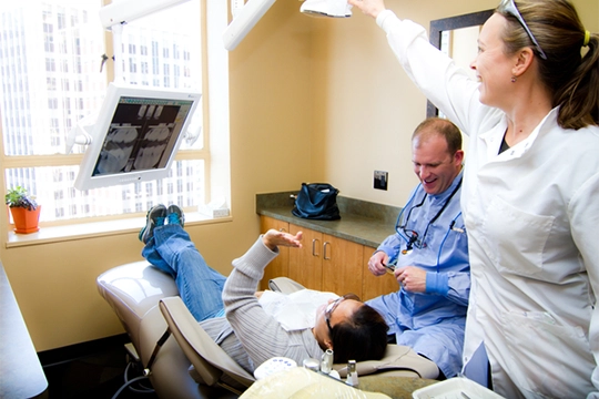 Dentist Thomas McKenny laughing With Patient And Assistant In Operatory