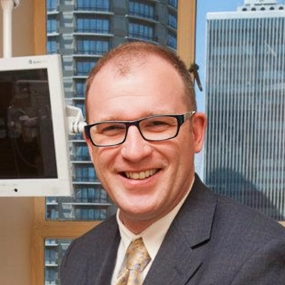 Dentist Thomas McKenny in the office smiling in suit and yellow tie