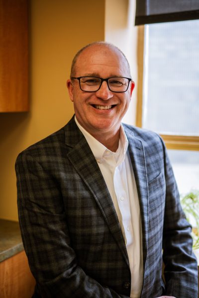 Dentist Thomas McKenny in the office smiling in suit